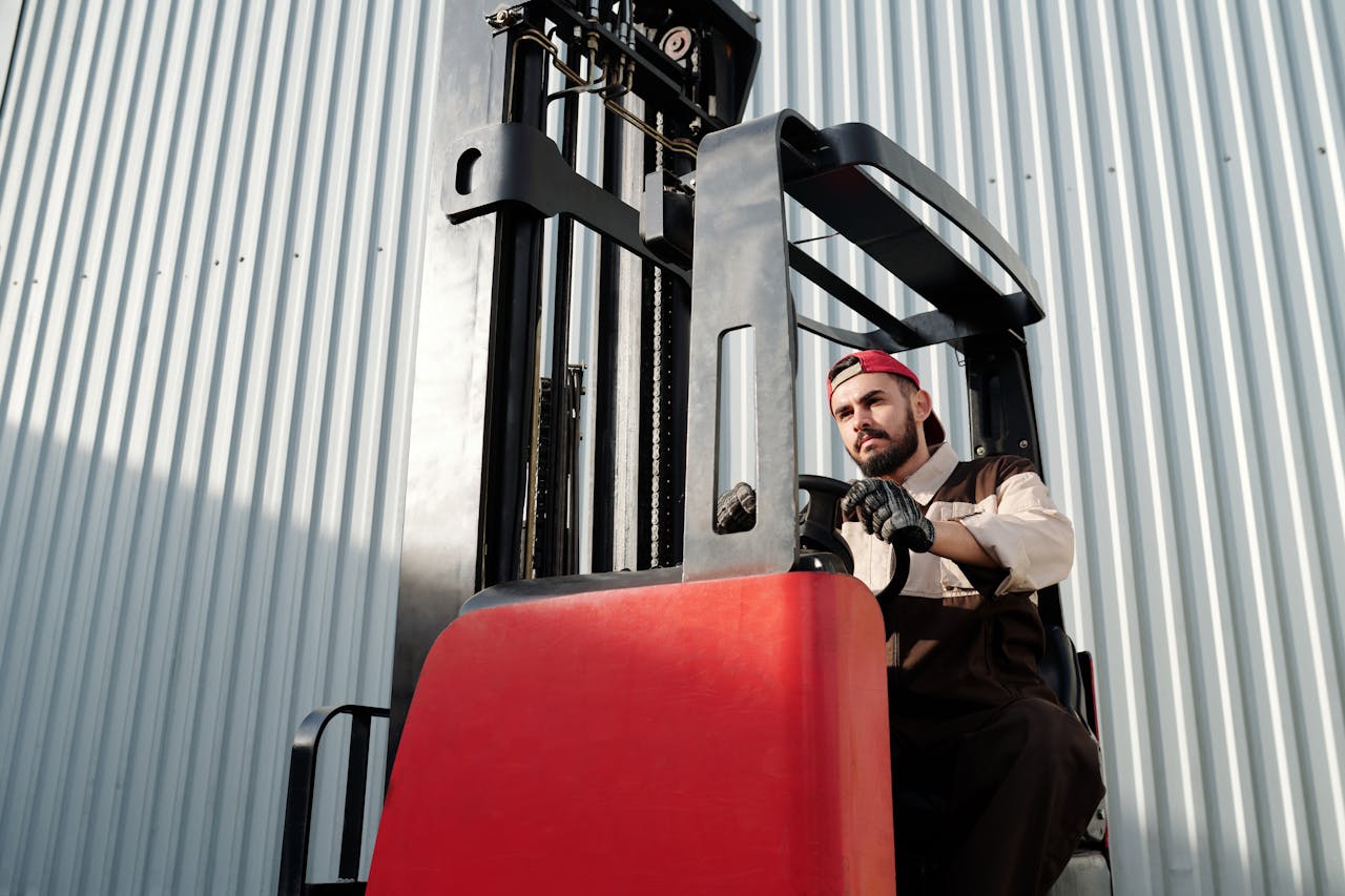 Man operating a forklift in an industrial setting outdoors.